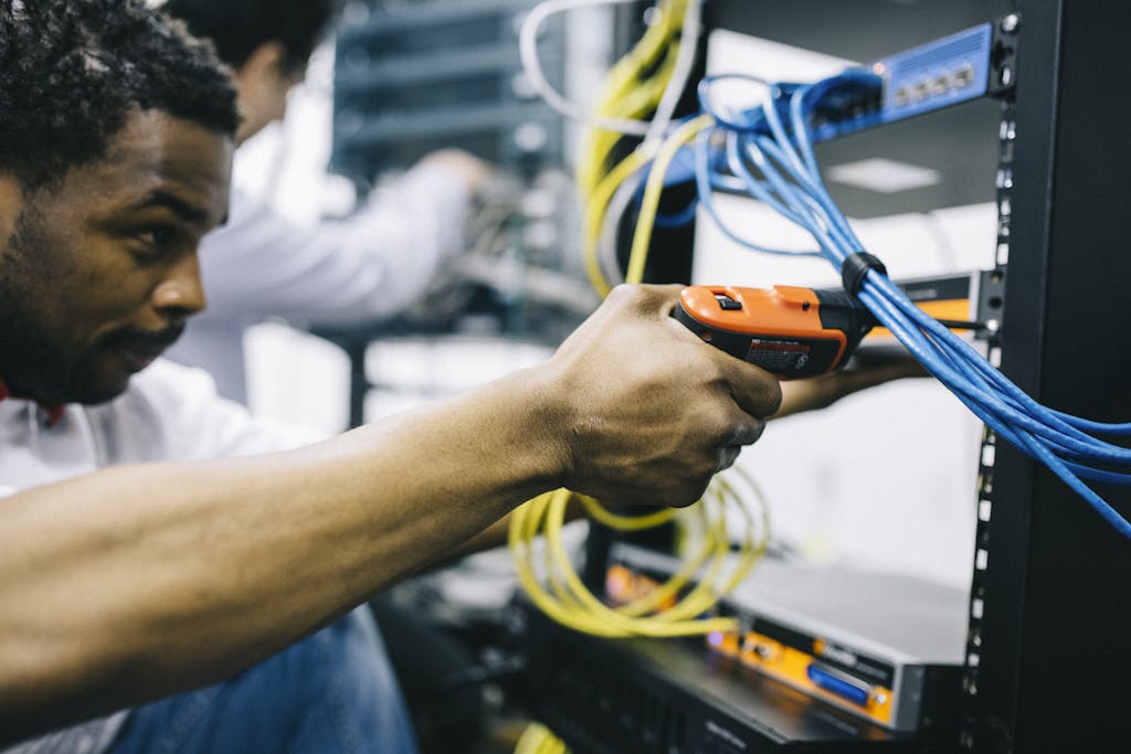 Crop focused ethnic engineer using electric screwdriver